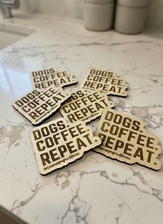 Wooden coasters with 'DOGS. COFFEE. REPEAT' text on a light background