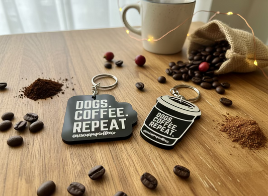 Two keychains with 'DOGS. COFFEE. REPEAT' text on a textured surface